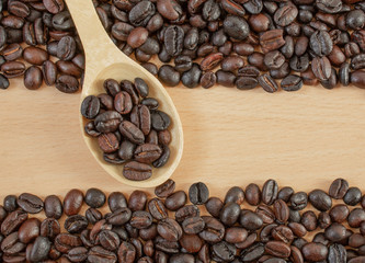 Coffee beans close-up on a wooden tray and in a wooden spoon.