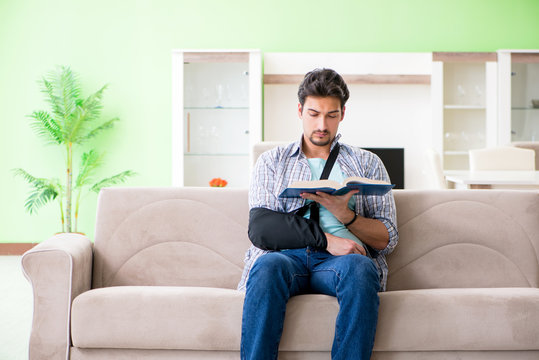 Young student man with hand injury sitting on the sofa 