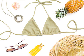 Tropical holiday concept. Pineapple fruits, sun glasses, straw hat and bikini swimwear on white background. Flat lay