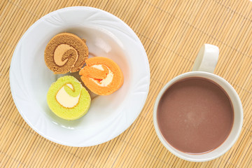 green chocolate orange cake roll on placed and cup coffee top view on mat background.