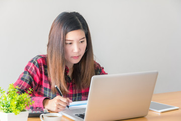 Young businesswoman using laptop in office with copy space