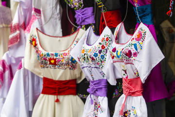 Mexican folk dresses displayed for sale in a mexican market