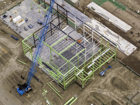 Aerial View Green Steel Frame Construction With Crane and Concrete Foundation