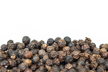 black peppercorns heap on white background.