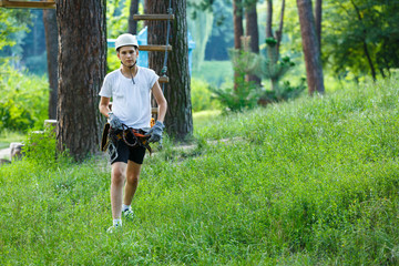 cute boy  in white t shirt in the adventure activity park with helmet and safety equipment. Young boy playing and having fun doing activities outdoors. Hobby, active lifestyle concept