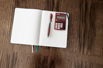 red calculator on notebook with red pen 