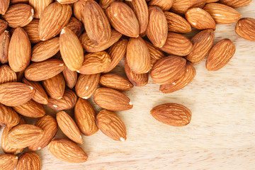 heap almonds top view frame or border on wooden background.