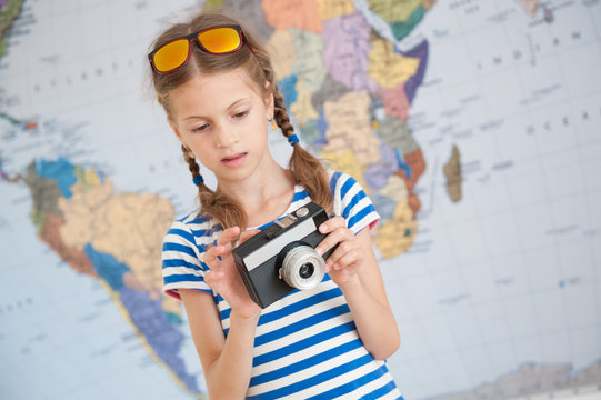 interested little girl studying camera in hands on world map background