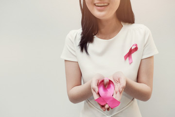 Young woman holding pink ribbon, breast cancer awareness, October pink concept