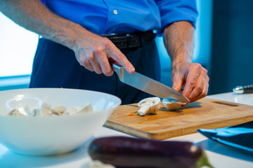 A man cuts a mushroom with a knife - champignons