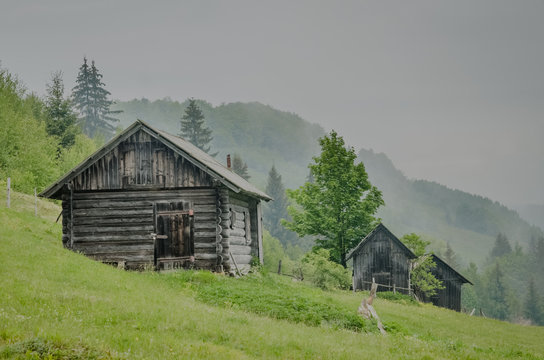 Wooden barn located on the slope of the hill, covered with forest and meadows. Ecology concept of clean environment. Natural background image. Taken at spring day at Carpathian mountains, Ukraine.