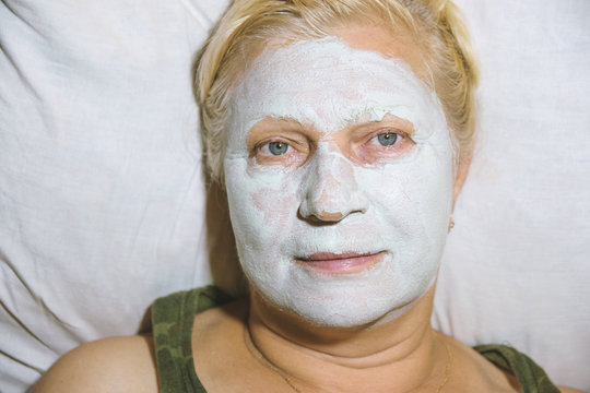 Aged woman with a cosmetic mask on face at home - beauty treatments concept.