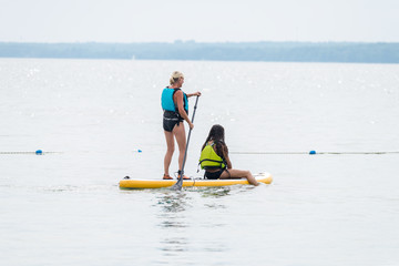 Motgher and daughter on a stand-up paddle board