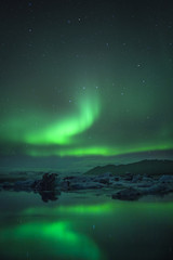 Fototapeta na wymiar Northern Lights over glacier lagoon in Iceland. Up north northern lights show.