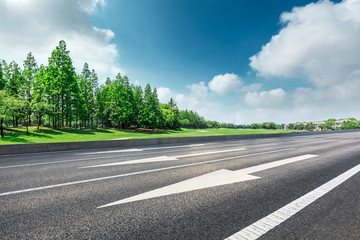 Asphalt road and green forest landscape under the blue sky