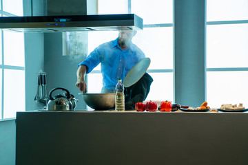 The man is cooking food in his home kitchen, he opened the lid of the pot,