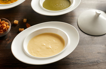Close-up view of bowl of cheese cream soup on wooden table