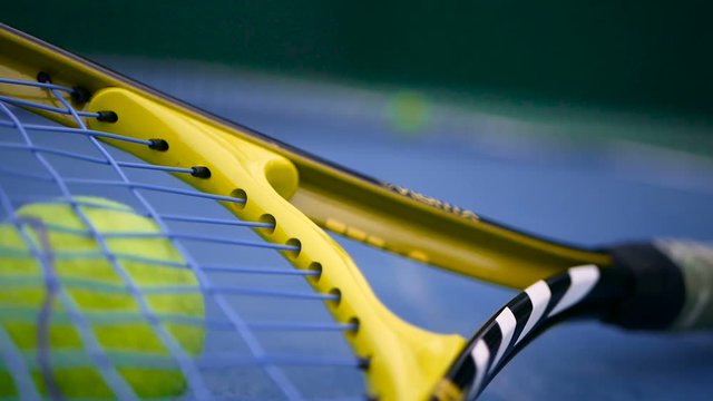 Close up of tennis equipment on the court. Sport, recreation concept. Yellow racket with a tennis ball in motion on a clay green blue court next to the white line with copy space and soft focus.