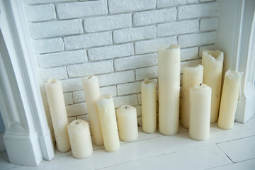 White candles in a decorative fireplace. Interior details.