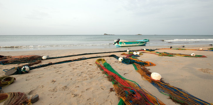 Small fishing boat next to fishing nets drying on Nilaveli beach in Trincomalee Sri Lanka Asia