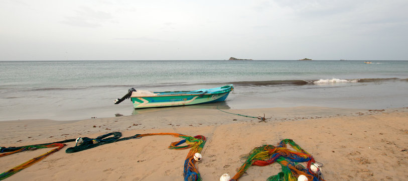 Small fishing boat next to fishing nets drying on Nilaveli beach