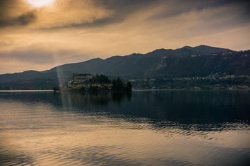 small and isolated island in the middle of the lake and the alps mountains at sunset