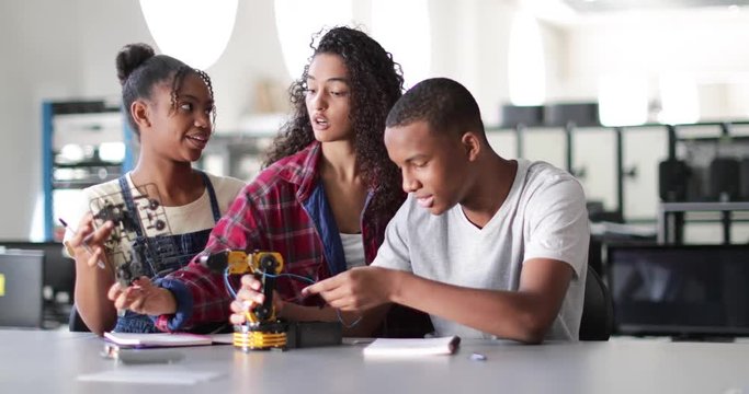High school students working on a robotic arm in class