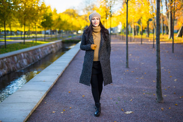 seasonal concept - attractive woman walking in autumn park