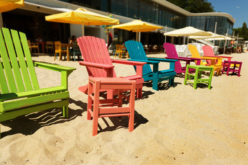 Fototapeta na wymiar Beach, multi-colored beach chairs, stools and chaise lounges. Beach umbrellas and beach furniture as a concept of relaxation, holiday, summer, spa