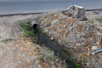 Dirty sewage along with sewage in an open ditch along the street. Dirty drainage, an open sewer...