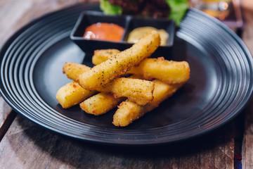 Seasoning French fries served with mayonnaise and thousand island sauce in black plate.
