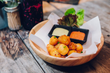 Fried Mozzarella Cheese Balls served with mayonnaise and thousand island sauce in wooden bowl.