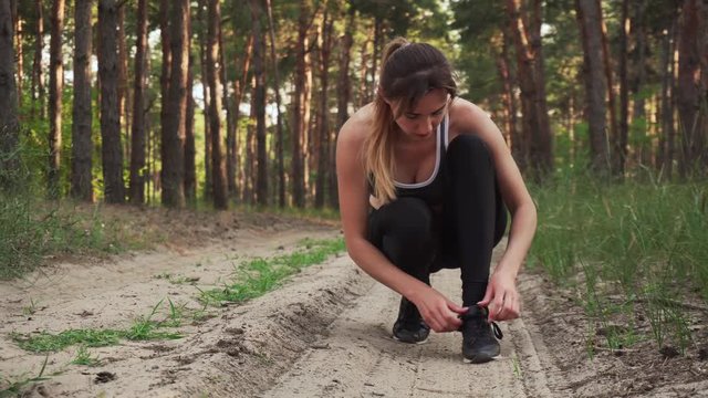 Athletic woman ties her shoelaces and starts running