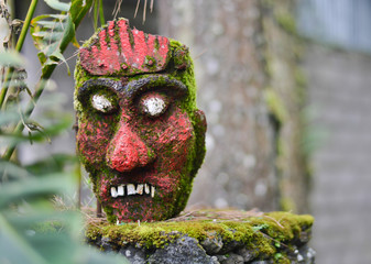 Red mask of the idol of the ancient religion of Bali with white protruding eyes on a stand clouse-up