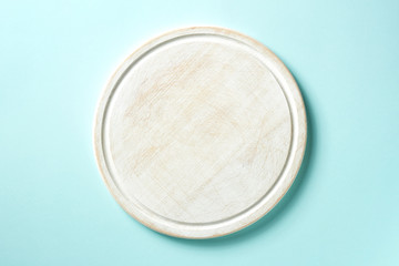 Wooden cutting board on blue background, from above