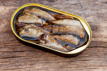 Open tin can of sprats on rustic wooden table
