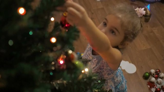Happy  kid decorate Christmas tree. Little girl decorating christmas tree with toys and balls.