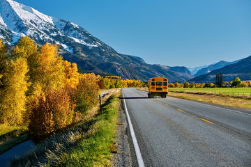 School bus on highway in Colorado at autumn
