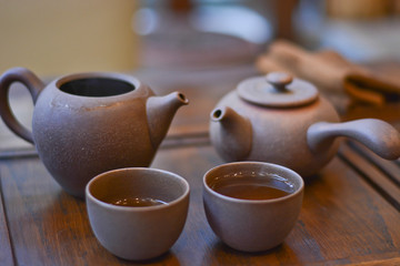 Chinese tea service for tea: wooden stand, clay cups with a tea and teapots close-up