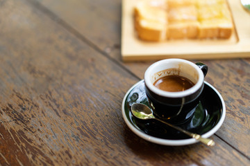 espresso coffee with brown creama in the cup and bread on wooden table