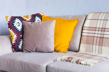 Cushions and plaid on the beige sofa close up with copy space. Sweet home and cozy concept