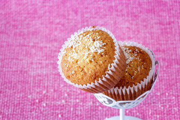 Homemade vanilla muffins with coconut powder. Pink background. Copy space. Selective focus. Blur motion.