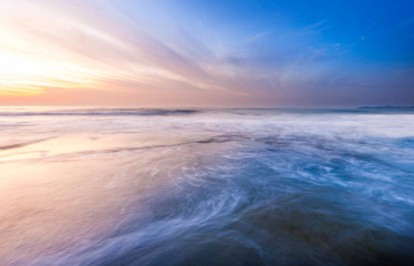beautiful waves trails during sunset. natural coastal rocks on the ground with colourful blue hour sky.
