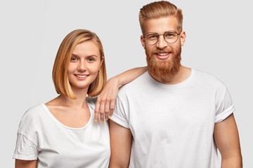 Obraz premium Cheerful family couple rejoice they become parents soon, stad close to each other, dressed in casual clothes, isolated over white background. Happy bearded male has date with pretty young female