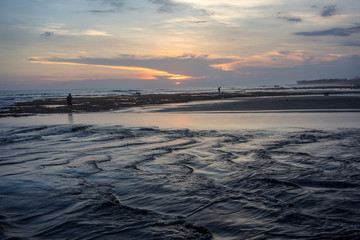 people on tropical beach at sunset with iconic red sky