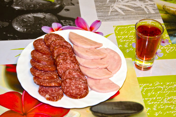 a plate with a sausage cut and a glass of wine. Homemade. A real, not staged photo