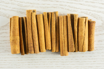 Lot of whole dry brown cinnamon stick in line flatlay on grey wood
