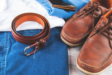 Man's clothes and leather accessories on wooden background
