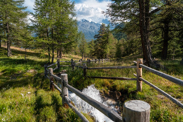 Holzzaun auf der Alpe mit eine wiltem Flußbach in der Schweiz im Wallis