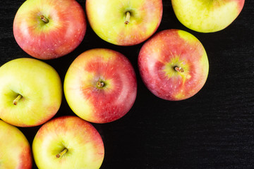 Lot of whole fresh red apple james grieve variety flatlay on black wood